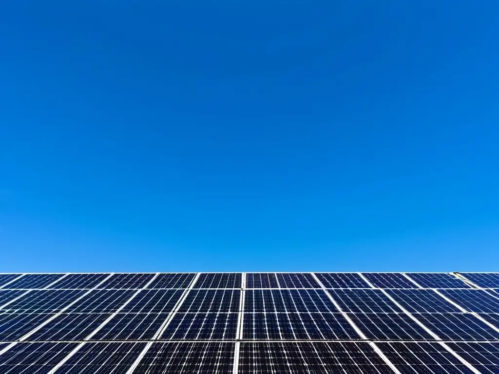 Arreglo de paneles solares en perfecta armonía con el cielo azul, simbolizando la reducción de la huella ecológica de la energía solar